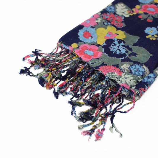 A close-up of a soft, floral-patterned vegan scarf with multicoloured fringe, shown against a white background.