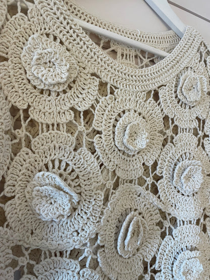 Close-up of a cream floral jumper, perfect for spring with large, circular flower motifs and intricate openwork detailing—an ideal sheer layering piece.