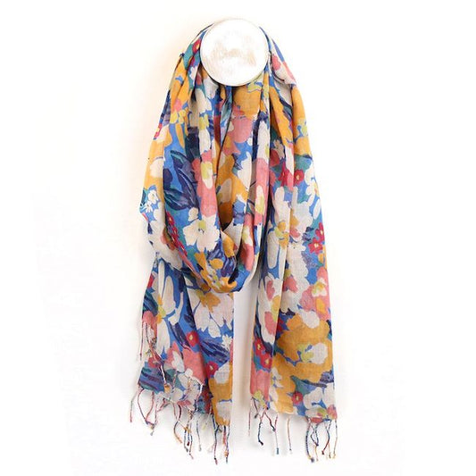 A lightweight summer scarf featuring a vibrant floral print and fringed ends is draped over a circular white hook against a plain white background.