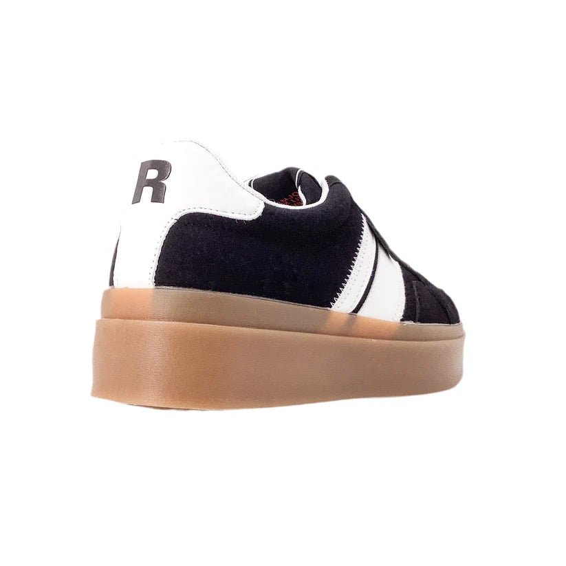 A black and white vegan trainer with a chunky tan sole, seen from the back left. The heel displays a large black letter R on a white panel.