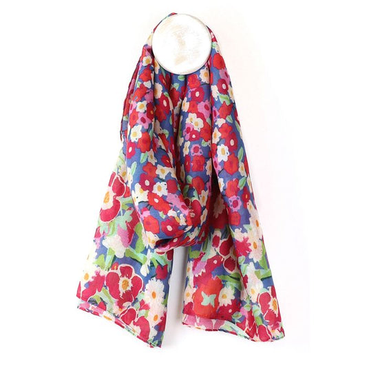 A colourful vegan-friendly scarf featuring a red, pink, and white floral pattern is draped over a round white hook against a plain background.