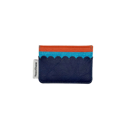 A slim, colourful card holder with a navy blue base, light blue scalloped accent, and orange top trim—this PVC card holder features a small white tag on the left side.