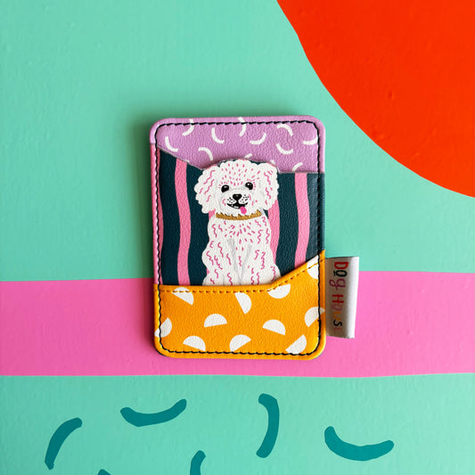 A charming card wallet showcasing a white dog with a collar, set on a vivid, abstract painted backdrop. This faux leather card holder brings style and colour to your everyday essentials.