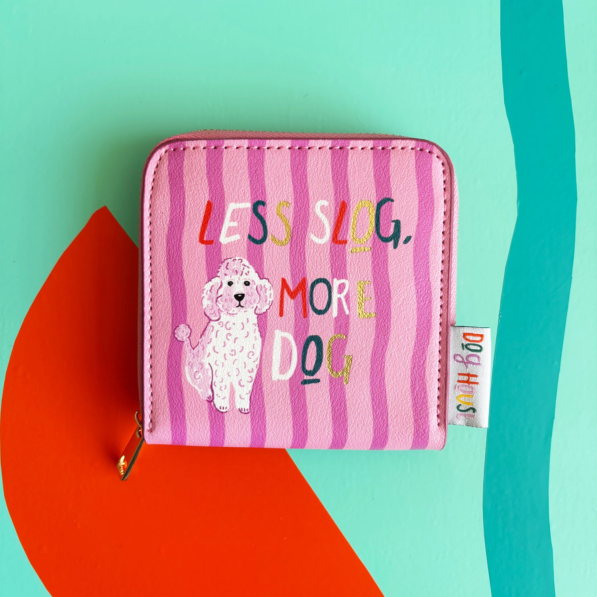 A pink zippered pouch from the Doghouse collection, featuring a cartoon poodle and the text LESS SLOG, MORE DOG on a colourful, abstract background—ideal for dog lovers.