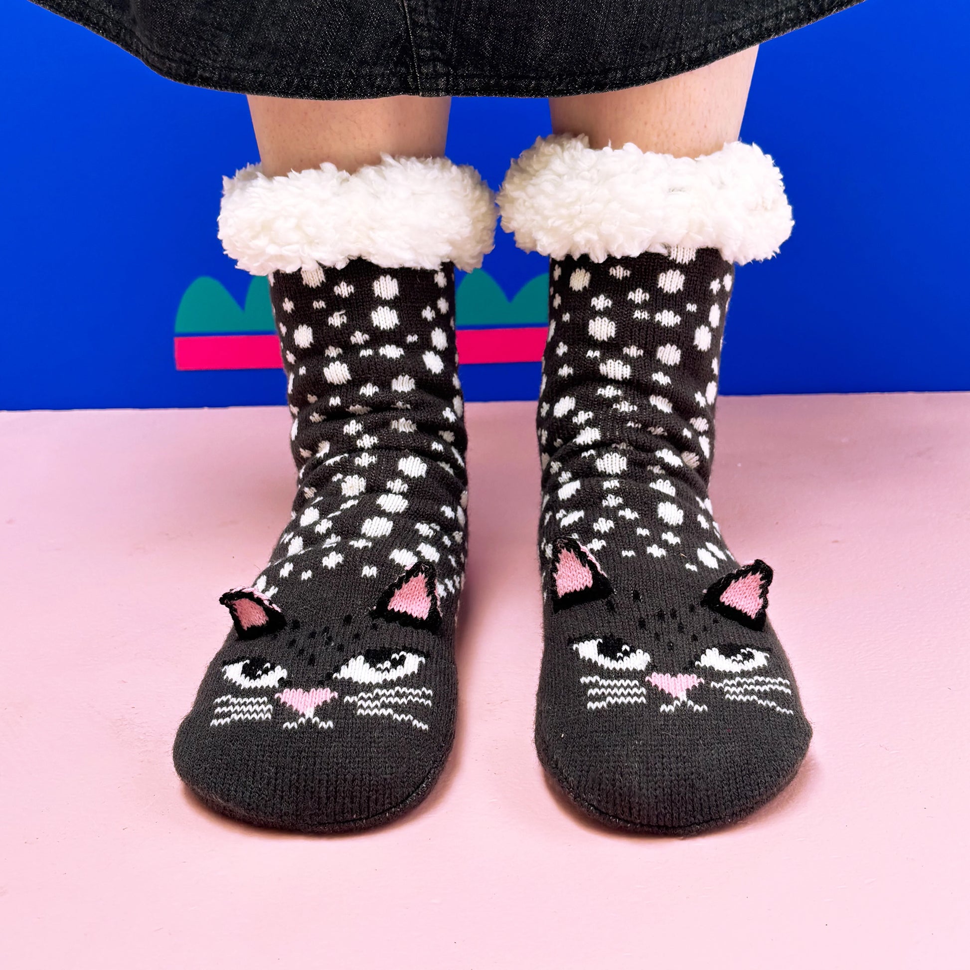 Person wearing Cat Face Slipper Socks with pink ears stands on a pink floor against a blue wall—ideal anti-slip socks and a cosy gift for cat lovers.