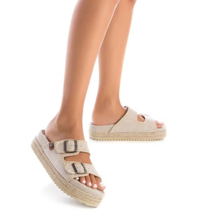 Person wearing beige vegan suede sandals with double buckle straps, standing on a white background.