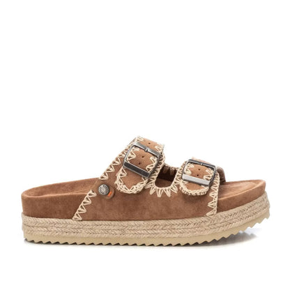 Brown double-buckle sandal made from vegan suede, featuring decorative stitching and a textured sole with espadrille-style jute trim.