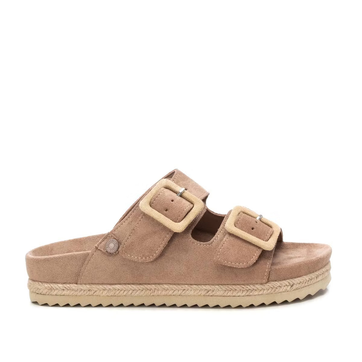 Tan vegan suede sandals with two broad straps, each adorned with a large beige buckle, and a textured beige sole. Side profile view against a white background.