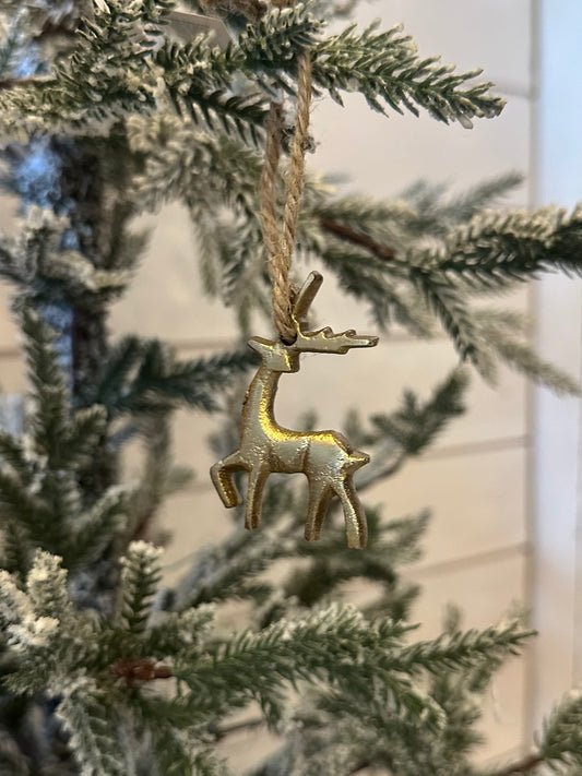 A gold hanging reindeer ornament dangles from a snow-dusted artificial Christmas tree, bringing festive charm to your holiday décor against a crisp white background.