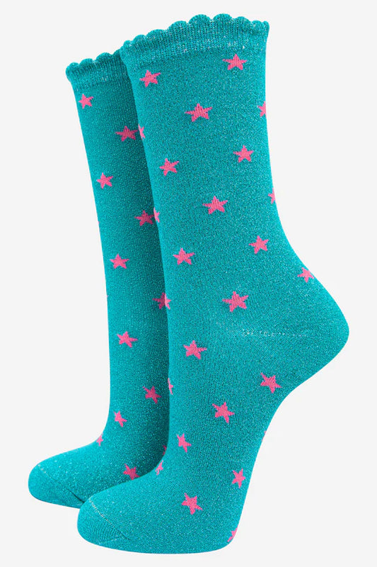 A pair of aqua crew socks featuring pink star detailing, a scalloped edge at the top, and crafted from a soft cotton blend glitter fabric.