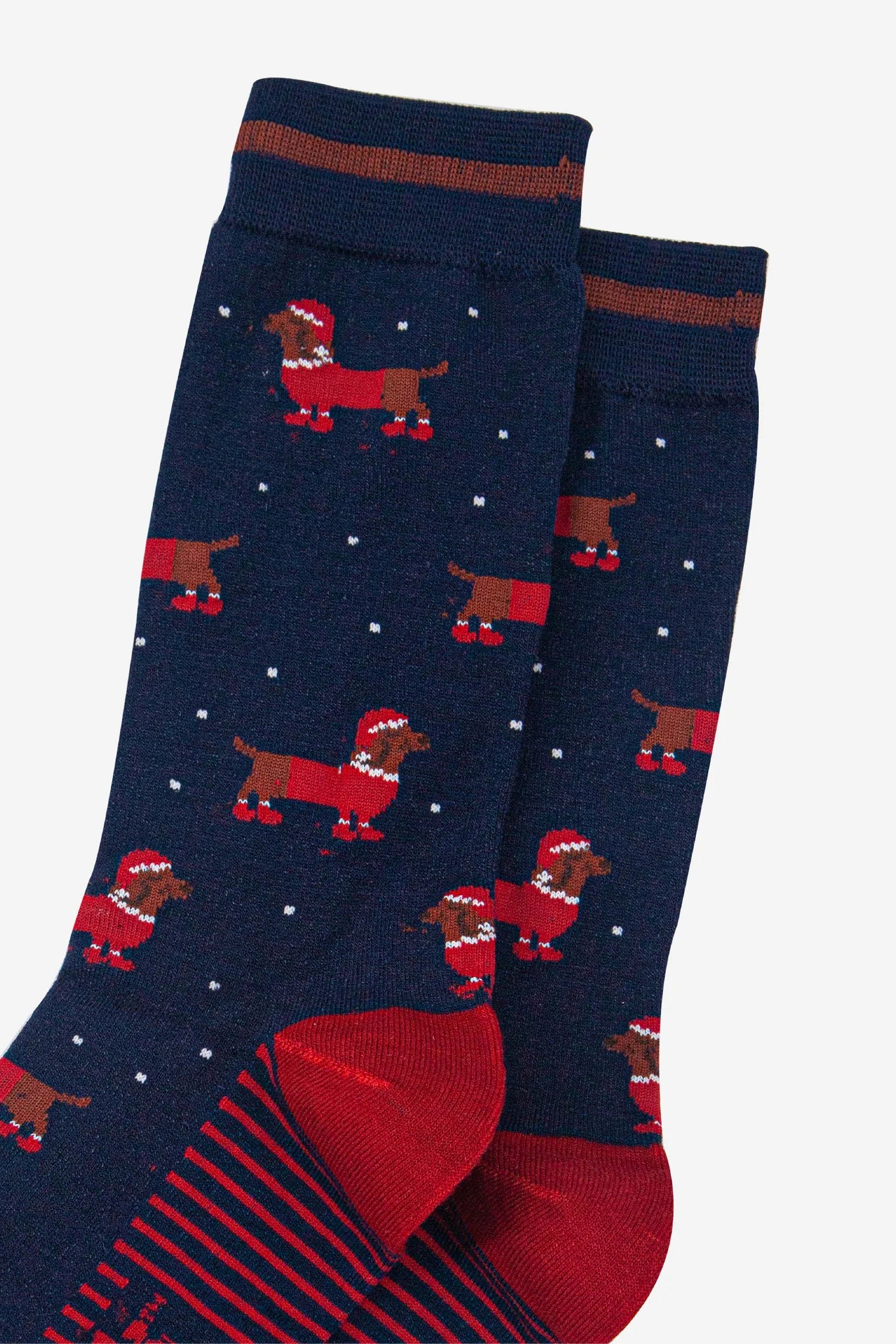 Navy blue vegan socks with red heels and toes, showcasing a playful design of Santa Sausage Dog socks—dachshunds sporting festive hats and scarves—ideal as a quirky Christmas present.