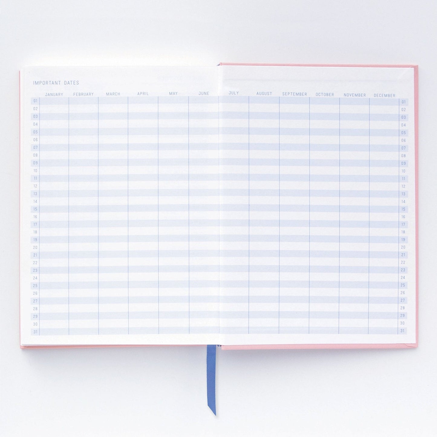 An open premium notebook with lay-flat binding displays a double-page Important Dates spread, empty monthly columns, rows numbered 1 to 31, and a blue ribbon bookmark at the bottom.