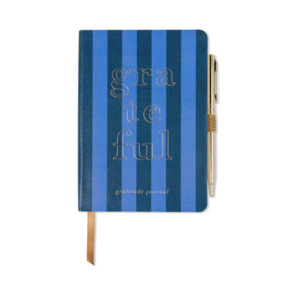 A blue striped gratitude journal with “grateful” in large letters on the cover, a gold pen attached, and a brown ribbon bookmark—ideal for daily mindfulness journalling.