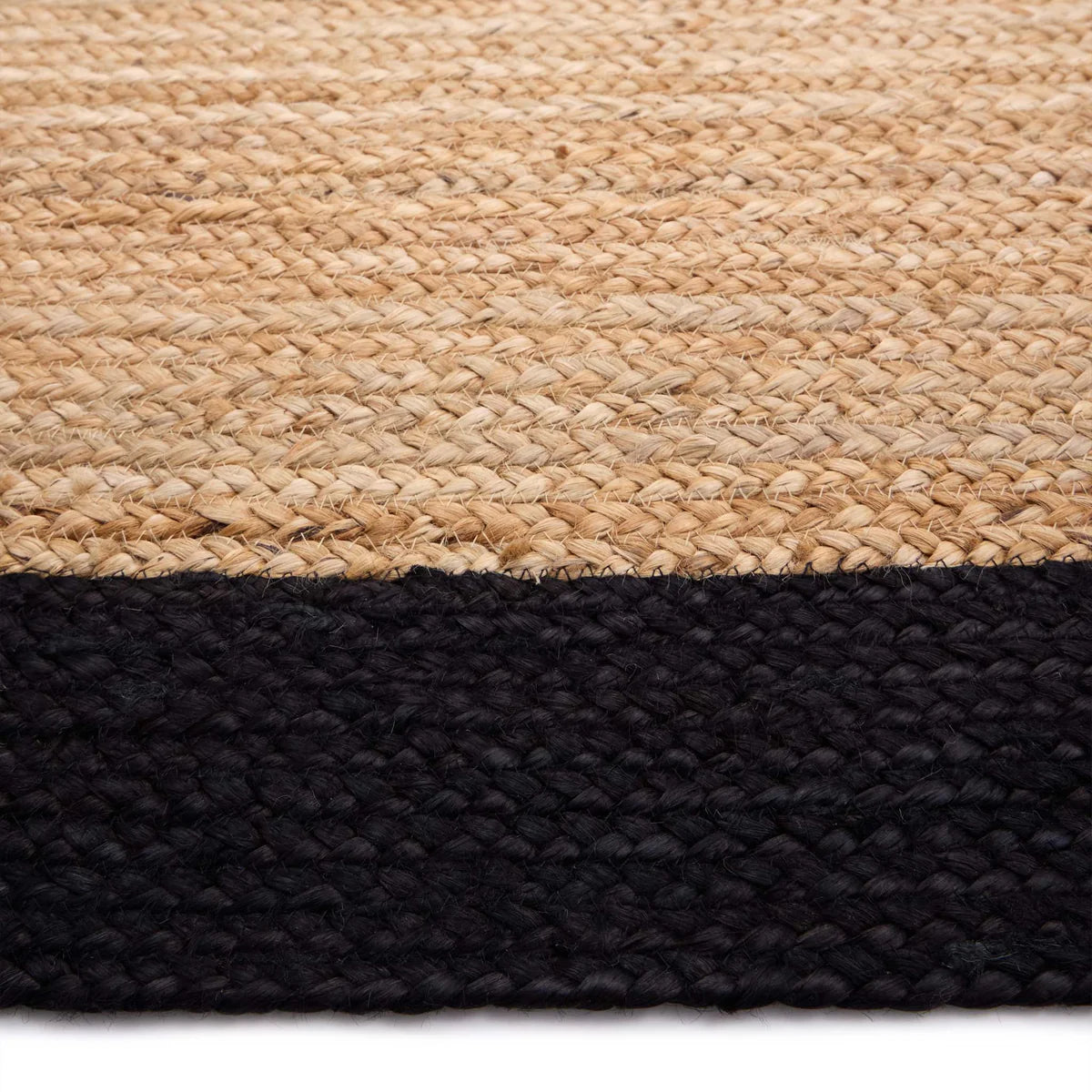 A close-up of an eco-friendly flooring option—a woven jute rug featuring a natural beige section at the top and a solid black border along the bottom.