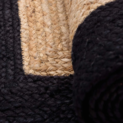 Close-up of a woven jute rug featuring a natural beige centre and a thick black border, partially rolled up at one corner—ideal for adding sustainable style to any room.