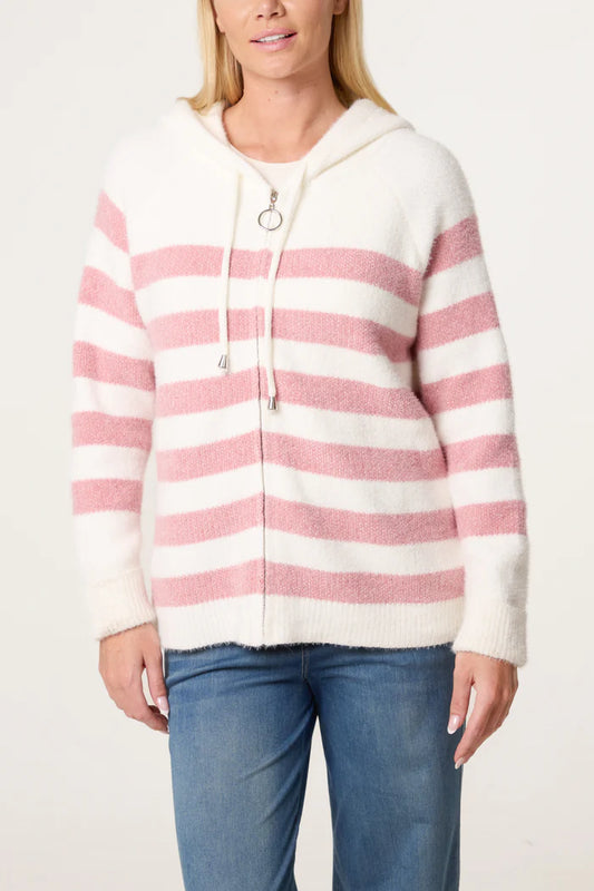 A person wearing a cosy, striped vegan-friendly hoodie with pink horizontal stripes and blue jeans, standing against a plain background.