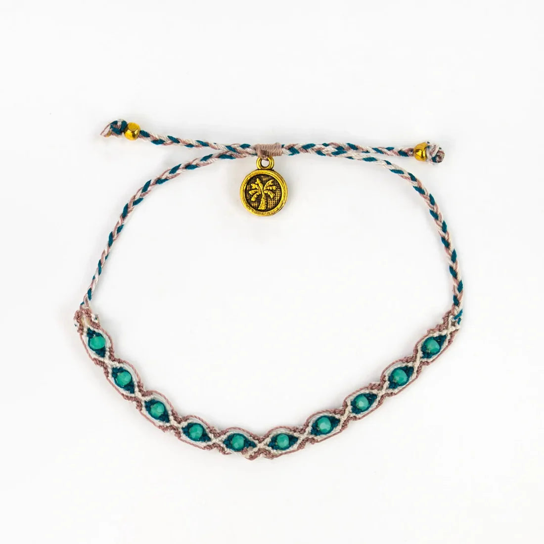 A handwoven bracelet with turquoise stones and a small, round gold charm engraved with a palm tree motif; this piece reflects classic Balinese jewellery style and is shown against a white background.