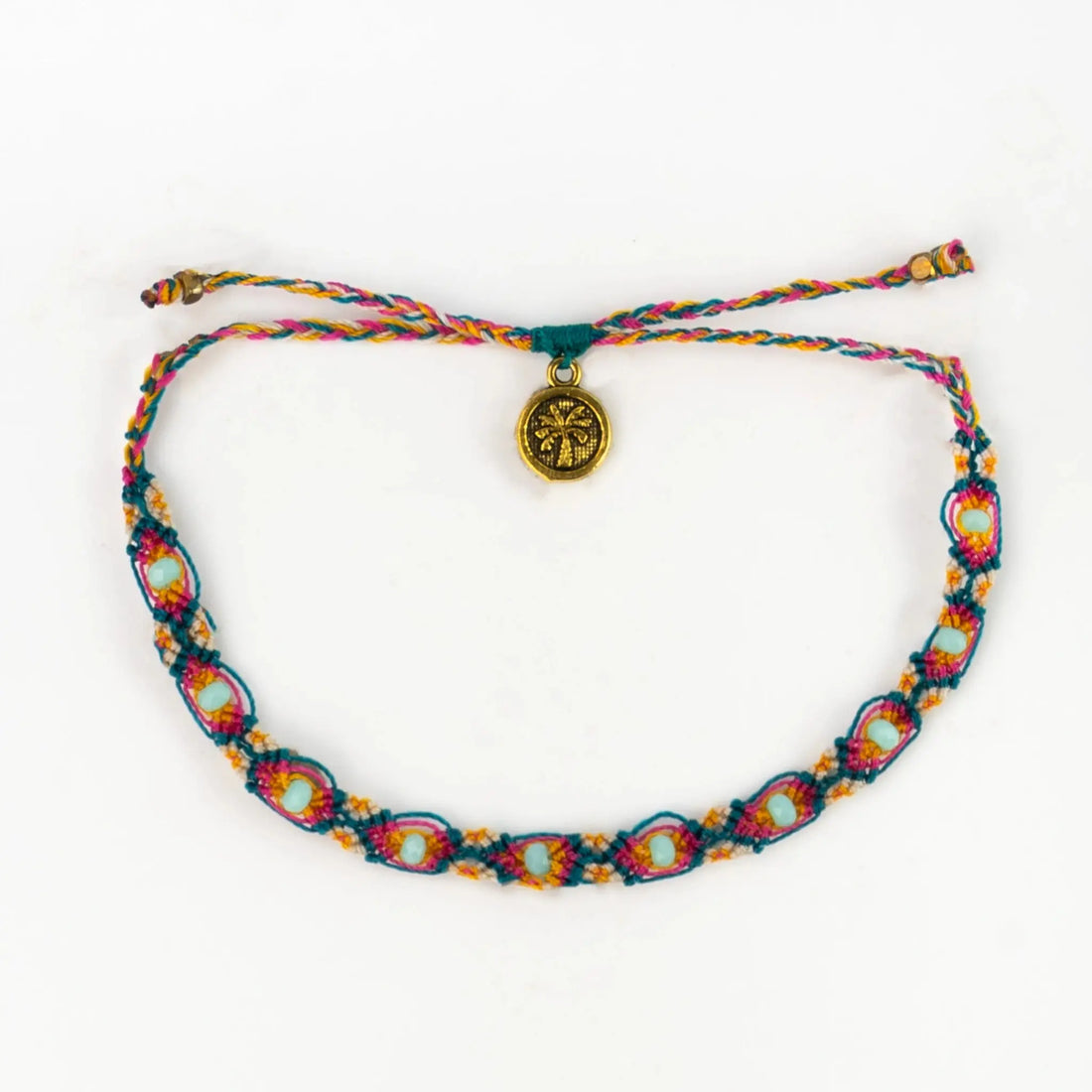 A colourful handwoven Bali bracelet with blue, orange, and pink patterns, featuring a round gold charm engraved with a design—an eco-conscious piece of jewellery displayed against a white background.