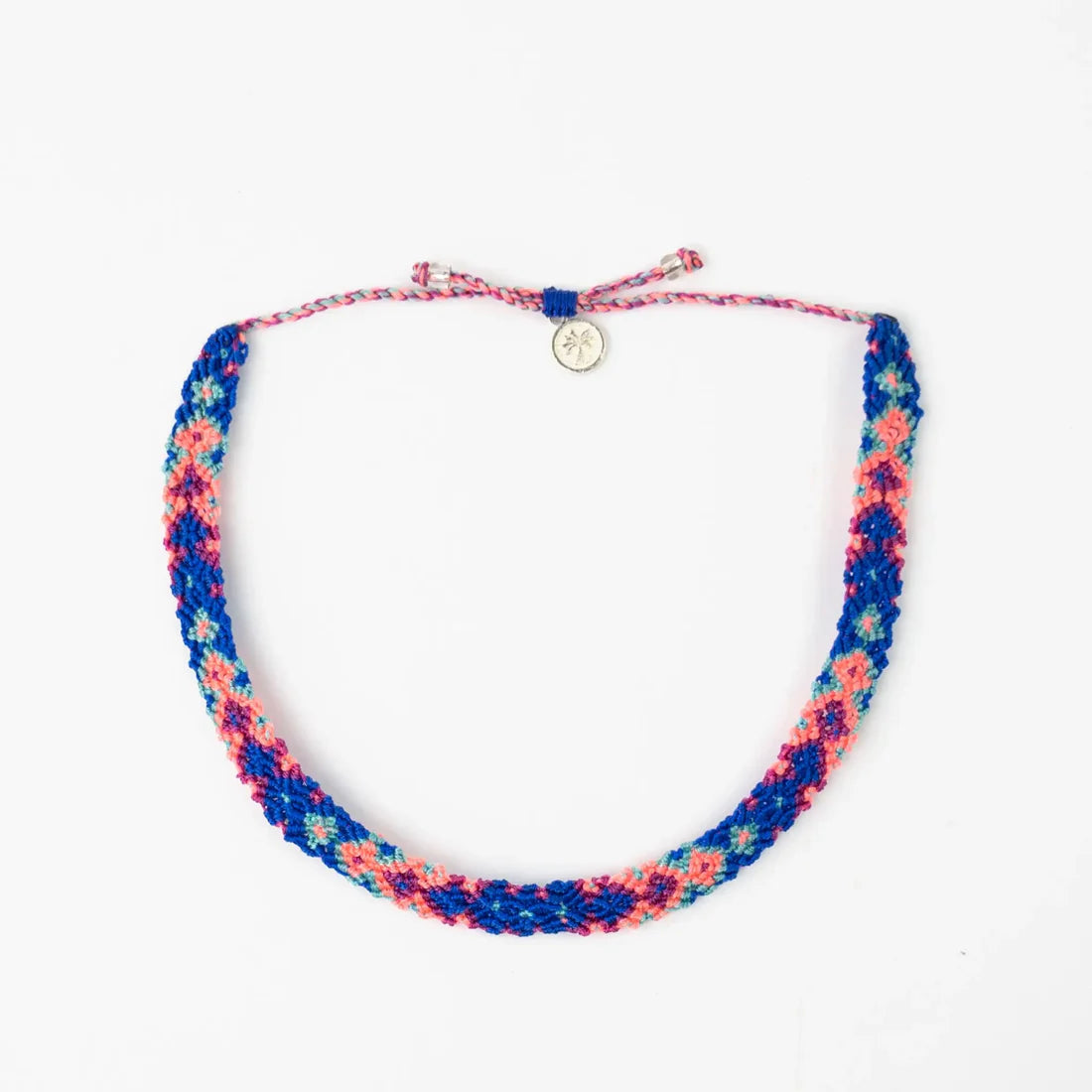 A colourful braided Leme Surf Bracelet showcasing a blue, pink, and red pattern, finished with a small round gold charm and an adjustable string fastening.