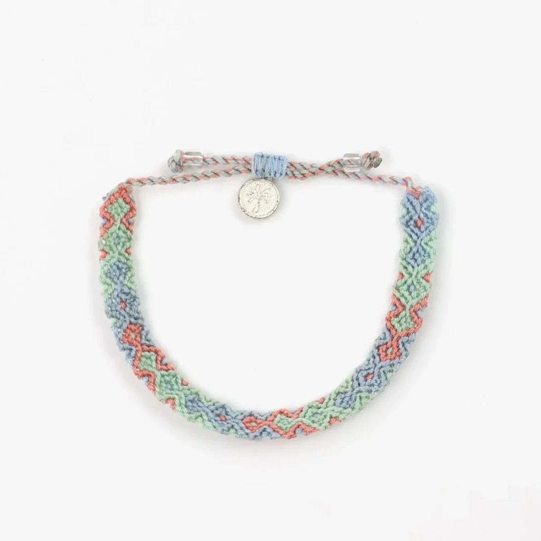 A handwoven macramé bracelet in pastel colours, featuring a zigzag pattern and fastened with a silver button clasp, shown on a white background—a distinctive piece of handmade Balinese jewellery.
