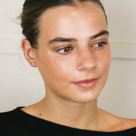 A woman with her hair tied back wears sterling silver reindeer earrings and a black top, gazing slightly to the side—a subtle hint of festive jewellery suitable for any occasion.