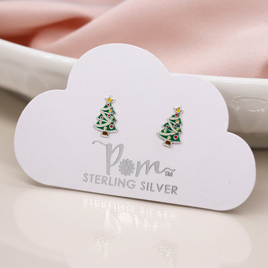A pair of sterling silver Christmas tree earrings with colourful decorations, displayed on a white cloud-shaped card against soft pink fabric—ideal festive earrings for lovers of holiday jewellery.