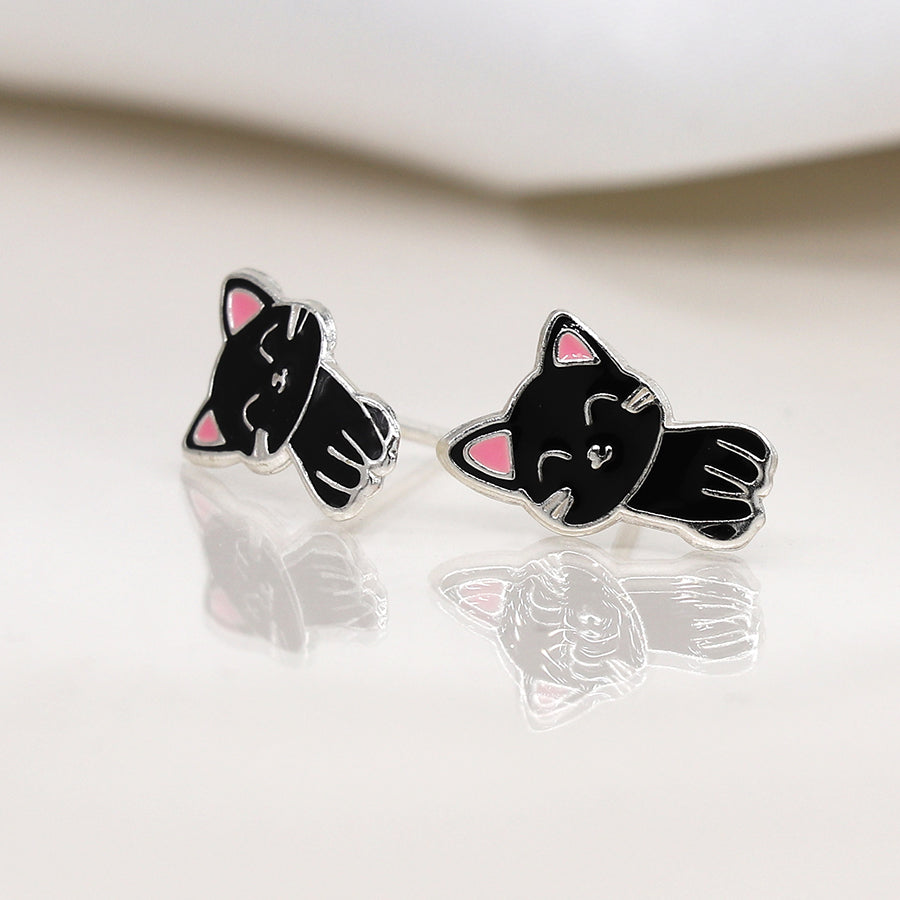Two sterling silver cat studs featuring black enamel designs with pink ears, exuding feline grace as they shimmer on a white reflective surface.