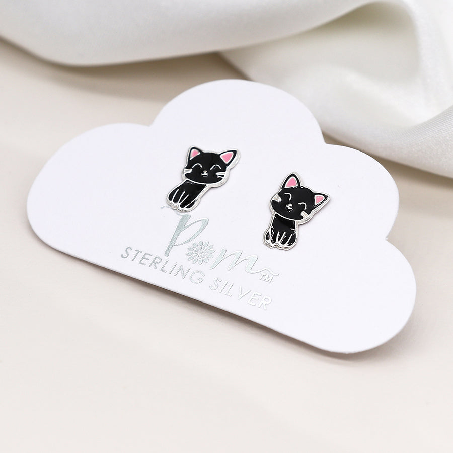 A pair of sterling silver cat studs, detailed with black and pink enamel, rests on a cloud-shaped card with the text STERLING SILVER, exuding feline grace.