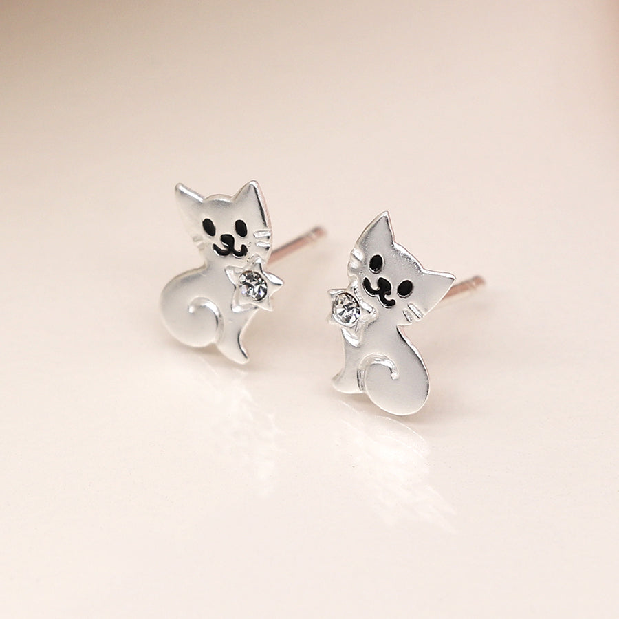 Sterling silver cat-shaped stud earrings feature black facial details and small gemstones, perfectly capturing a playful cat design against a light-coloured background.