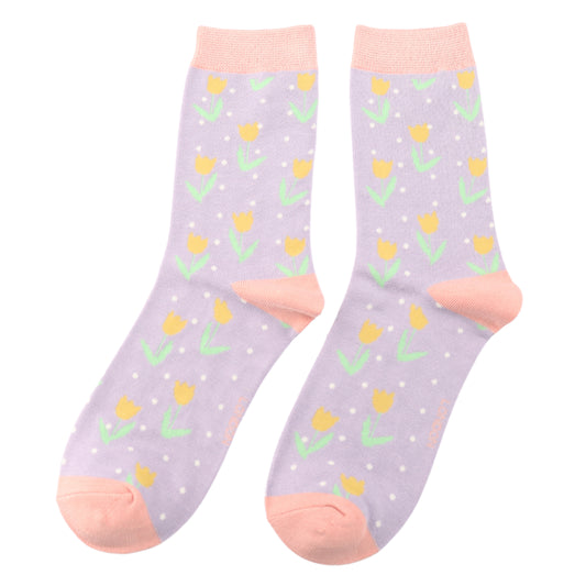 A pair of vegan-friendly socks in lavender, featuring yellow tulip patterns, white spots, and peach cuffs, heels, and toes.