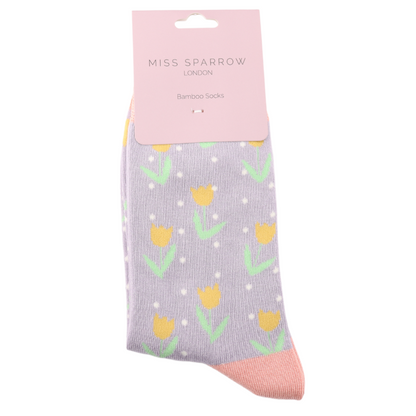 A pair of Tulips Spots Mauve Socks in light purple bamboo and cotton, featuring yellow tulips and white spots, packaged with a pink Miss Sparrow London Bamboo Socks label. Vegan-friendly socks.