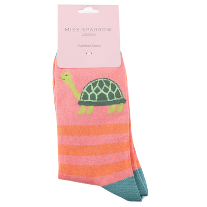 A pair of pink and orange striped bamboo and cotton socks with a green turtle design, featuring a turtle and stripe motif, packaged and labelled Miss Sparrow London Vegan Socks.