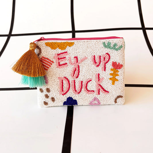 A white Ey Up Duck pouch with colourful embroidery of British slang, featuring decorative patterns, a brown and turquoise tassel, and a zip fastening—a fun gift inspired by classic British sayings!.