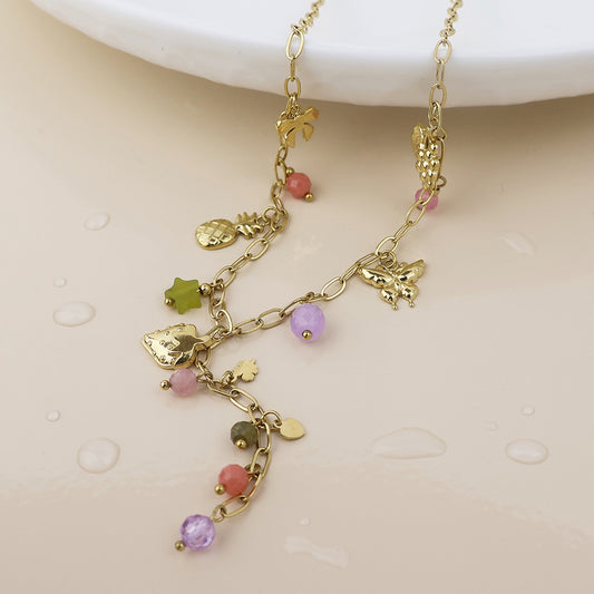 Waterproof gold-plated necklace featuring fruit charms and colourful beads, shown on a light beige surface with water droplets.