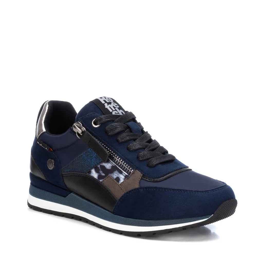 A navy blue women’s vegan trainer featuring black laces, a side zip, patterned detailing, a removable insole, and a white and black sole—stylish and PETA-approved vegan.