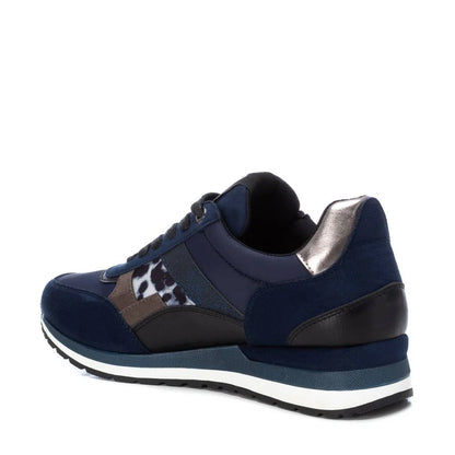 A navy blue women’s vegan trainer with black, metallic silver, and animal print accents, white midsole, dark outsole, and removable insole, seen from the back left side.