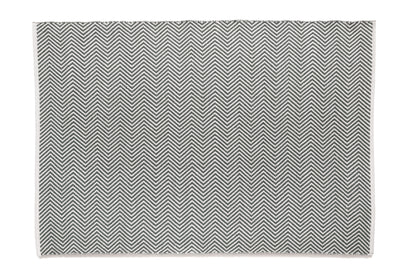 This rectangular, monochrome rug features a UV-stable design with a repeating chevron pattern in black and white, sustainably crafted from recycled plastic bottles.