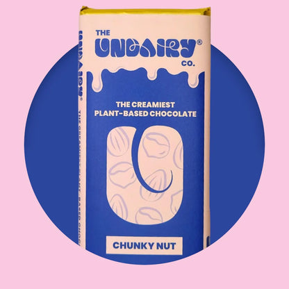 A blue and yellow chocolate bar wrapper labelled The UnDairy Co. The creamiest no-dairy chocolate, Chunky Nut, with a vegan twist against a pink and blue background.