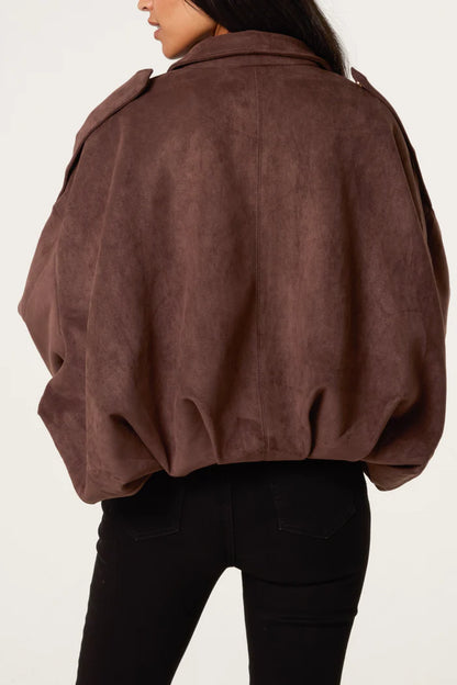 A woman seen from behind wearing a chocolate suedette jacket with broad shoulders, paired with black trousers.