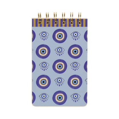 A small lined notepad with a blue cover displaying a repeating pattern of stylised eyes and concentric circles, made with premium paper for a smooth writing experience.