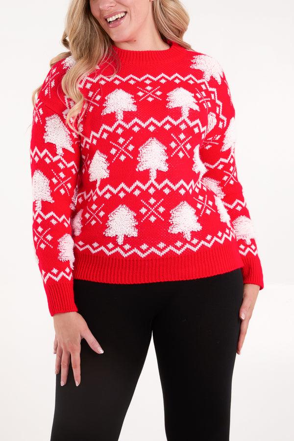 A person is wearing a red Christmas tree jumper featuring white geometric patterns, crafted from vegan materials, teamed with black trousers and standing against a white background.