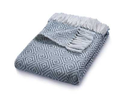 A folded blue and white patterned sustainable throw, crafted from recycled plastic bottles with fringed edges, is displayed against a white background.