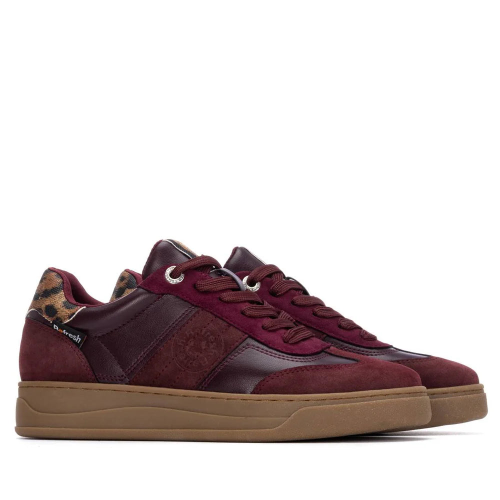A pair of burgundy womens trainers with suede and leather panels, gum rubber non-slip soles, and a leopard-print detail on the heel.