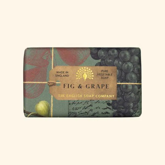 A bar of eco-friendly Anniversary Fig and Grape Soap by The English Soap Company, wrapped in decorative fruit-themed paper with a brown band indicating it is pure vegetable soap.