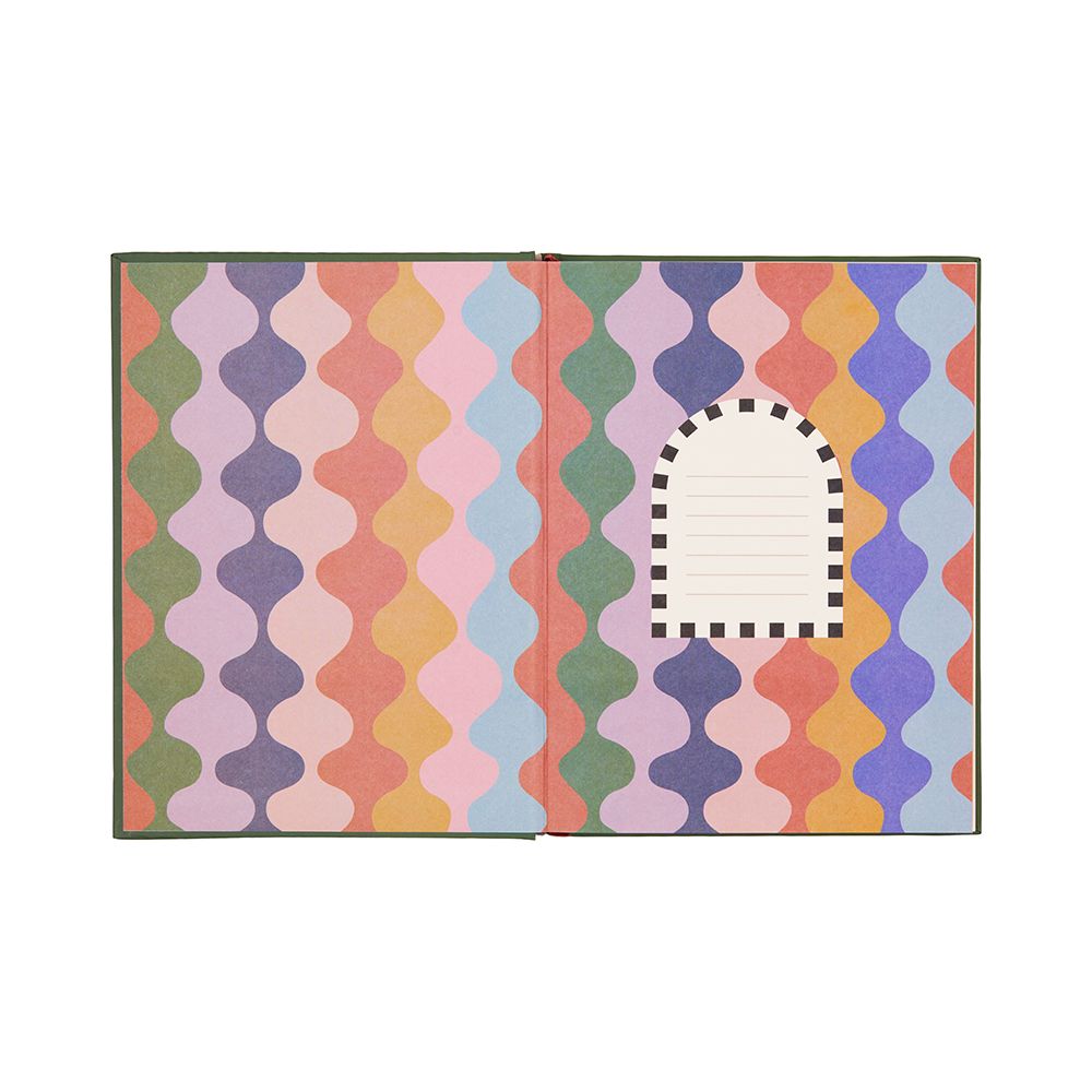 An open hardback journal shows colourful, wavy-patterned endpapers and a blank, arched nameplate with a dotted border on the right-hand page.