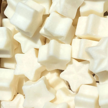 A collection of star-shaped and square-shaped white marshmallows, reminiscent of vegan wax melts, viewed from above and closely packed together.