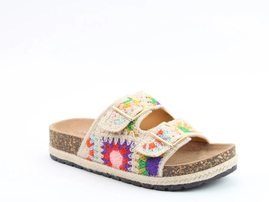 A single vegan-friendly bio-sandal with a contoured footbed, colourful crochet patterns, and adjustable twin buckles on two straps rests on a cork sole against a white background.