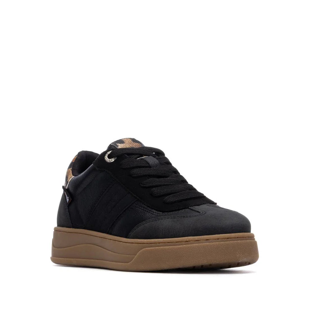 A pair of black trainers with matching laces, a brown gum sole, and a patterned heel detail, shown against a plain white background.