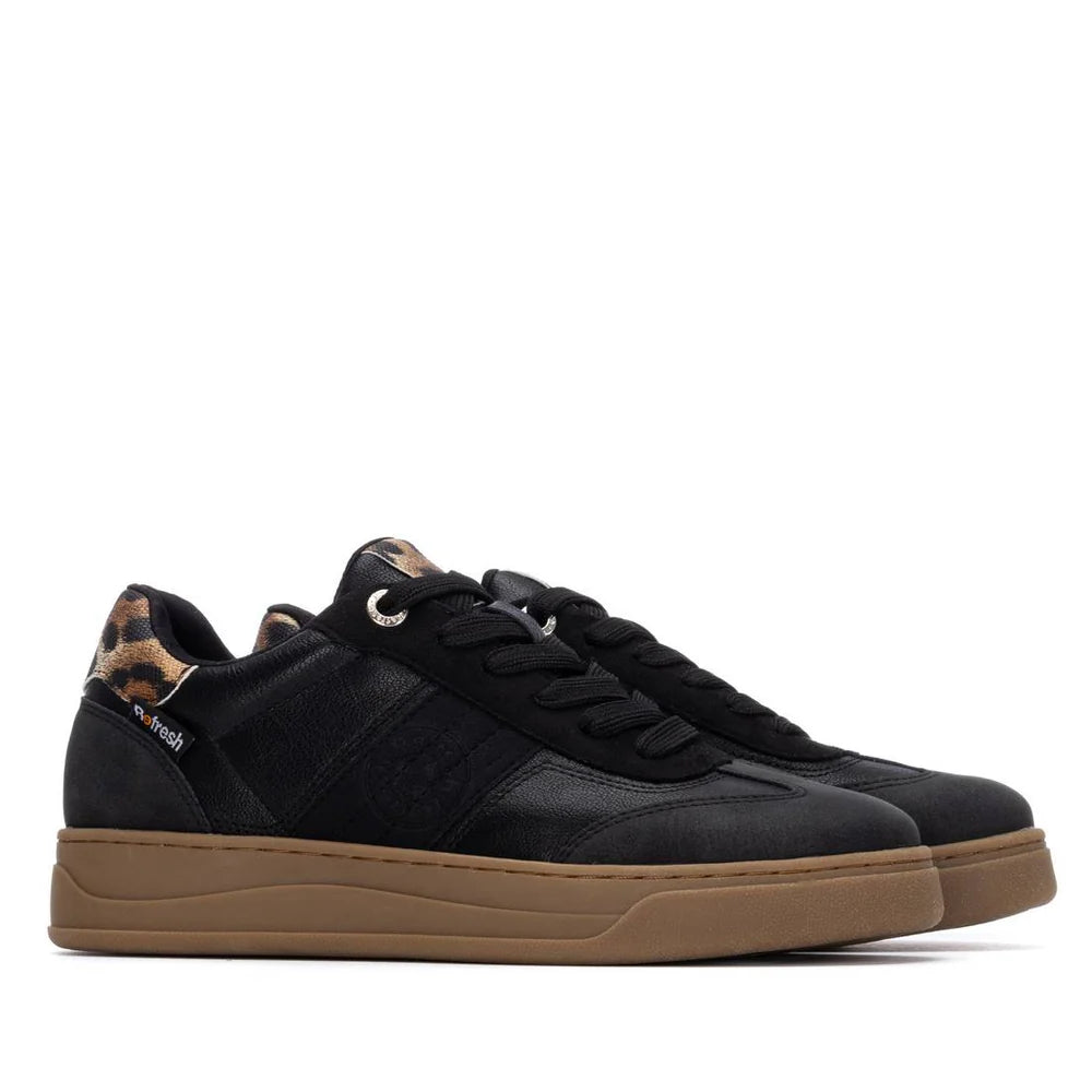Pair of black vegan trainers with brown soles, black laces, and a leopard print detail on the heel, shown against a white background.