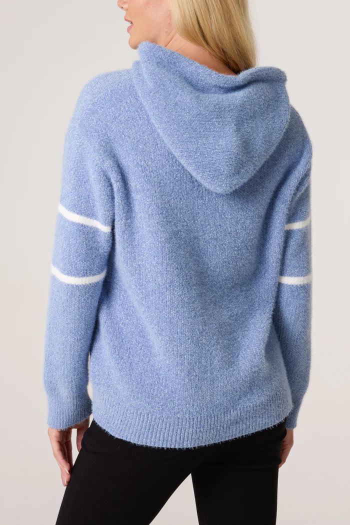 Person seen from behind wearing a cosy baby blue hoodie with white stripes down the sleeves, paired with black trousers.